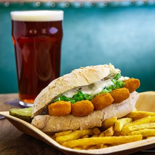 A pint of Chaucer Ale next to a fish finger sandwich at the Green Dragon in Bungay