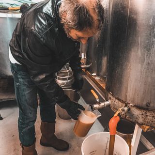 Rob Pickard dispensing the last dregs of beer from a small fermenting vessel at the Green Dragon brewery in Bungay